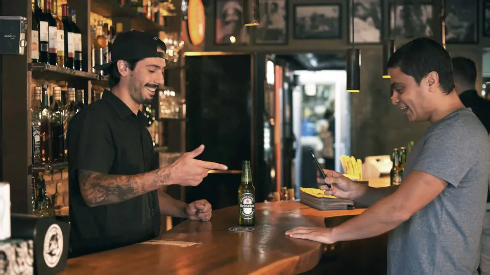 Bartender e cliente no balcão com a ação da Heineken